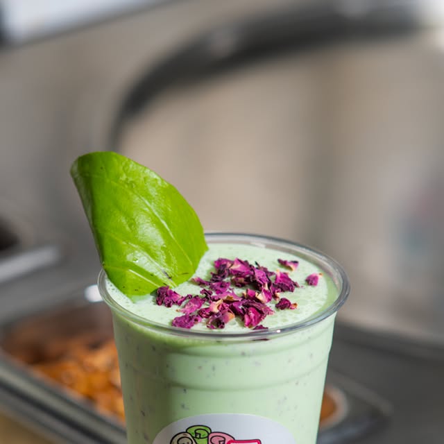 Paan ice cream in a cup garnished with a fresh leaf and rose petals